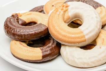 Close up of ring shaped chocolate biscuits in a porcelain plate isolated on white background