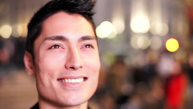 Happy asian man watches a large screen that lights his face