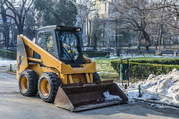 Fototapeta na wymiar Yellow municipality excavator doing spring cleaning