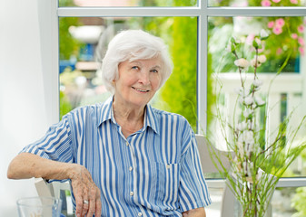 Seniorin sitzt im Wintergarten