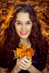 Naklejka premium Autumn portrait of beautiful curly smiling girl with leaves