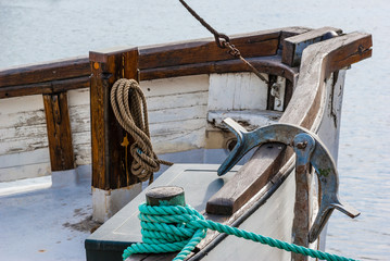 Fishing boat with anchor and ropes in harbor.