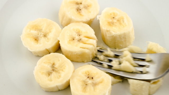 Mashing banana pieces into paste with fork