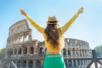 Young woman rejoicing in front of colosseum in rome, italy