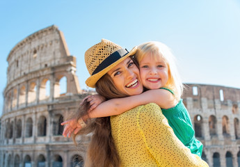 Naklejka premium Portrait of mother and baby girl hugging in front of colosseum