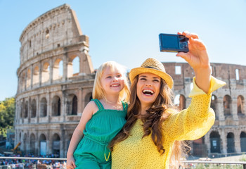 Naklejka premium Happy mother and baby girl making selfie in front of colosseum