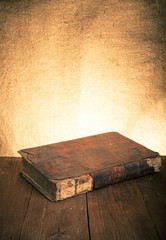 Ancient book on the old wooden table. Toned