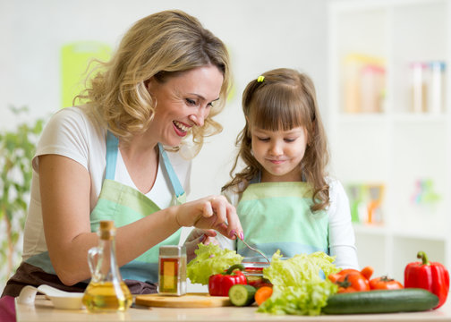 mother and her child preparing and tasting healthy food