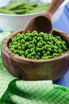 Wooden bowl with fresh sweet petite peas and scoop