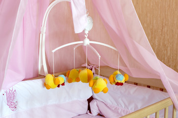 Fototapeta na wymiar Toy carousel on the cot with orange linen