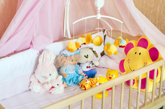 Various soft toys in the cot with orange linen