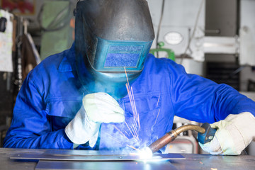 professional welder welding metal pieces in steel construction
