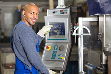 Worker operating a machine with control panel