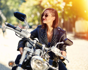 Fototapeta premium Biker girl in a leather jacket on a motorcycle