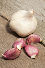 Garlic and cloves of garlic on wooden board.