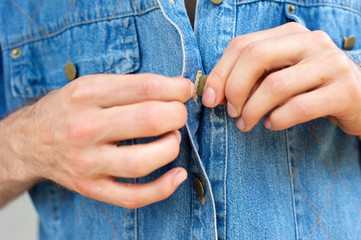 Man hands unbuttoning denim blue shirt