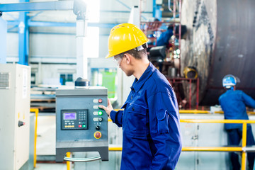 Worker in factory at machine control panel