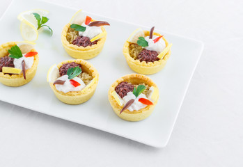 Salty mini tarts stuffed with green and black olive paste