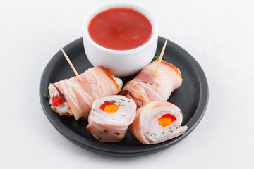 Tasty rolls of bacon, chicken meat, vegetables, tomato dip