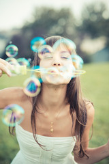 beautiful young woman with white dress blowing bubble