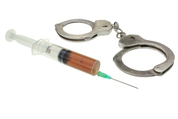 Handcuffs and Syringe With Brown Liquid Isolated