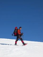The man in snowshoes in the mountains.