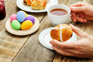 Easter Breakfast. Man holding the bun with a cross and a cup of