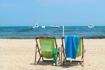 Beach with green chairs and boats in water