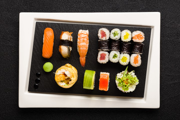 Sushi on white plate with black stone surface