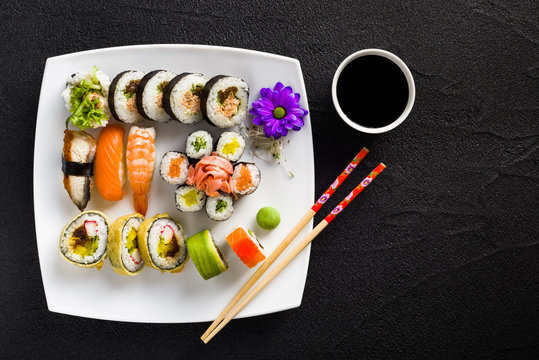 Sushi on white plate on a black stone table