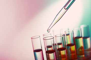 Pipette adding fluid to the one of test-tubes