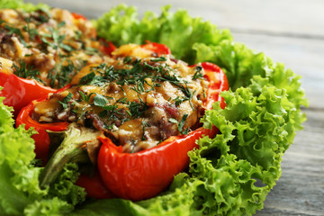 Stuffed red peppers with greens on plate on wooden table