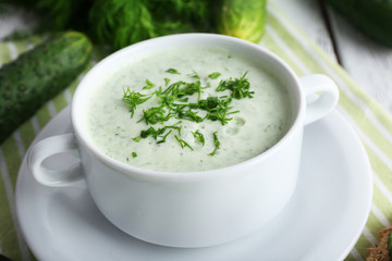 Cucumber soup in bowl on color wooden table background