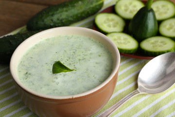 Cucumber soup in bowl on rustic wooden table background