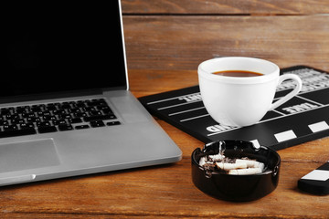 Movie clapper with laptop and cup of coffee on wooden