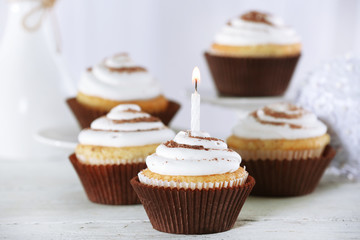 Delicious birthday cupcakes on table on light background