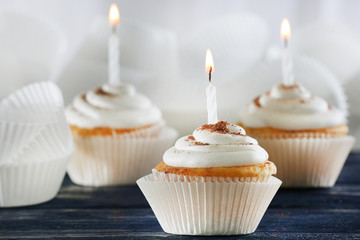 Delicious birthday cupcakes on table on light background