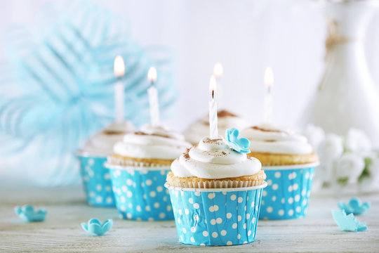 Delicious birthday cupcakes on table on light background