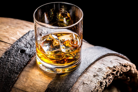 Glass of whisky and old wooden barrel