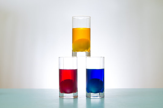 three glasses with colored liquid and eggs inside