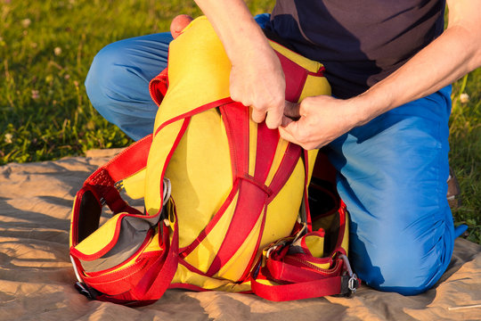man packs  parachute in  backpack outdoor