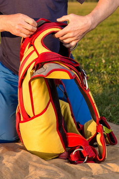 man packs parachute in  knapsack outdoor