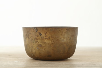 Old brass bowl on wooden table