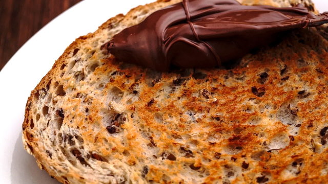 Spreading of chocolate hazelnut butter on whole wheat toast