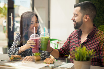 Happy young couple drinking a healthy smoothie in a juice bar
