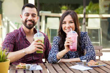 Pretty couple drinking smoothies during a date in a cafe