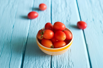 Naklejka na ściany i meble Red cherry tomatoes in bowl on blue wooden background