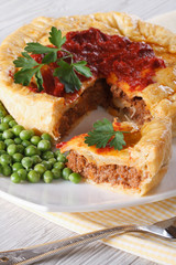 Pieces of meat pie and a garnish of green peas. Vertical