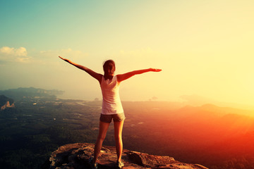 strong confident woman hiker open arms at on mountain peak rock