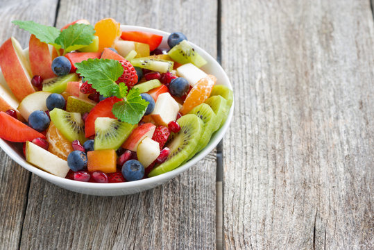 Fruit and berry salad in a bowl on a wooden background
